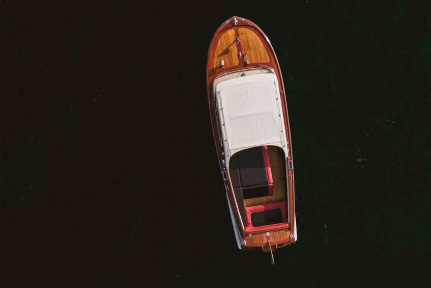 A small wooden boat with a white cabin and red accents, floating on dark water. 4