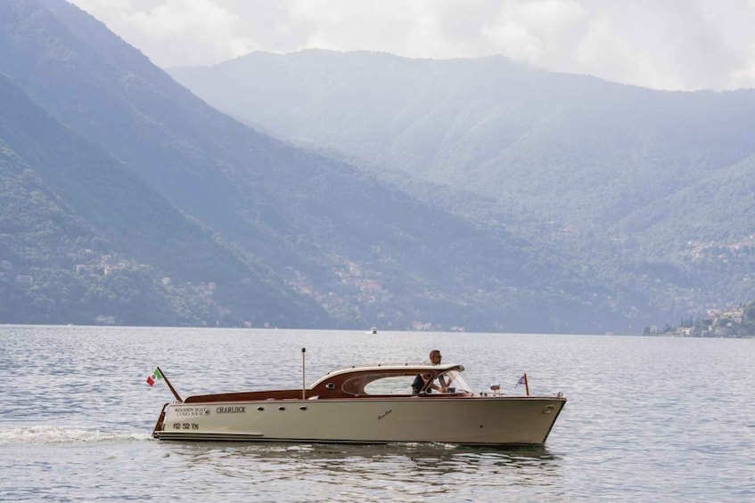 A wooden boat named CHARLOCK on a calm lake with mountains in the background. 3