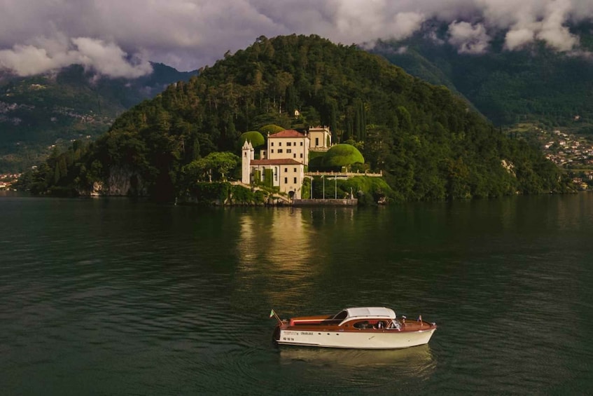 A boat on calm water with a large, lush green mountain in the background. 2