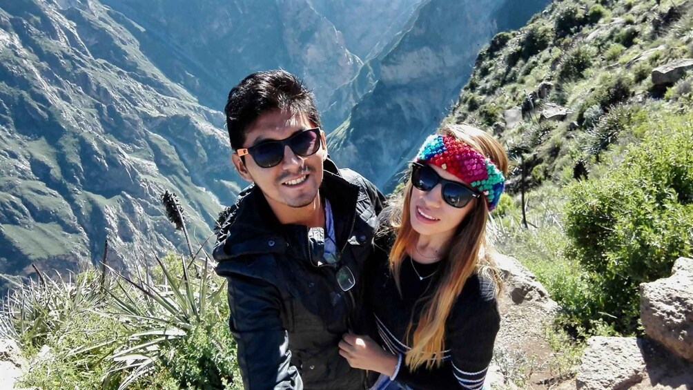 Two people standing on a mountain trail with a mountainous landscape in the background. 5