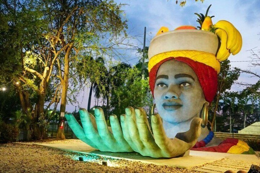 Un'ampia scultura raffigura una mano con un cappello colorato e delle banane. 1