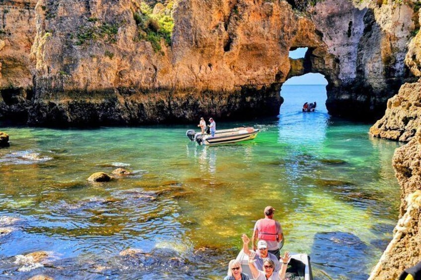 A rocky coastal area with clear water, a boat, and people on the shore. 1