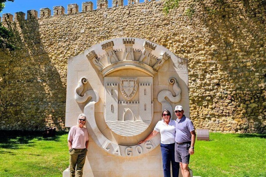 A stone wall with a coat of arms and the word 'LAGOS' at the base. 5