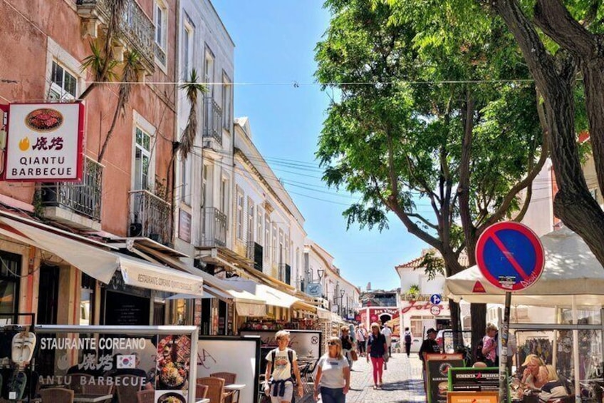 A street with a barbecue restaurant, a no parking sign, and pedestrians. 3