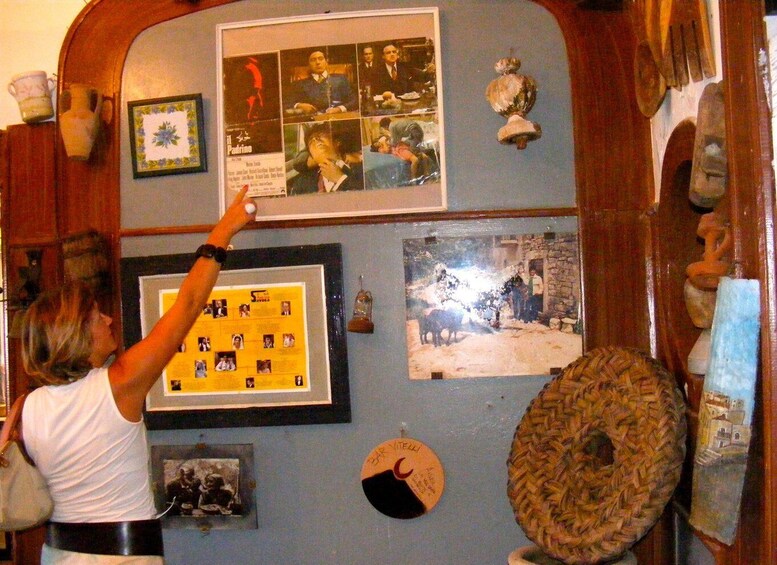 A wall with various framed pictures and a circular object. 5