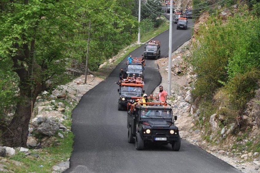 A convoy of vehicles on a winding road surrounded by greenery. 4