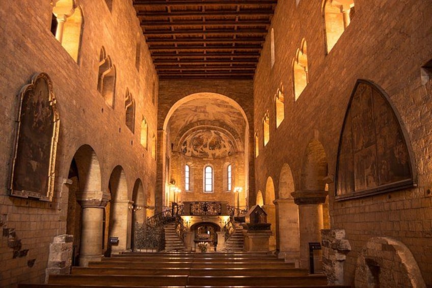 En interiörbild av en katedral med välvda tak, målade glasfönster och ett altare i mitten. 5