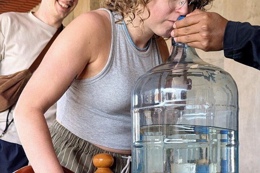 A person pouring liquid from a large glass container. 3