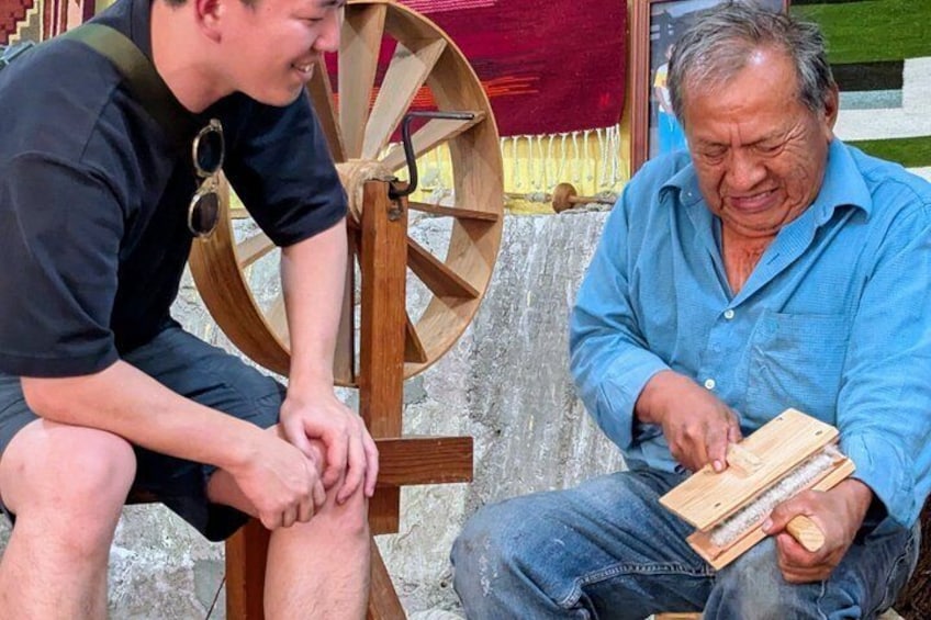 Two men sitting on a bench, one holding a wooden object. 5