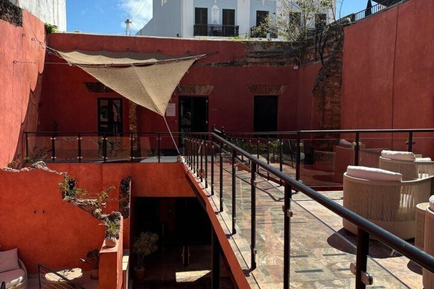 A courtyard with red walls, a staircase, and a shaded area. 5