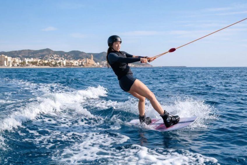 A person wakeboarding on a body of water with a coastal town in the background. 1