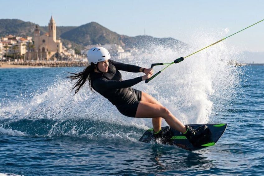 A person wakeboarding on water with a helmet, a wakeboard, and a rope. 2