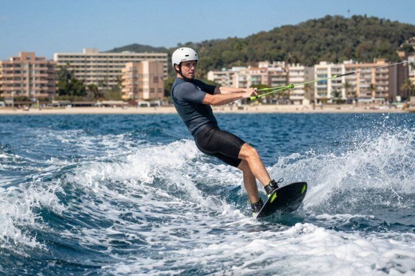 A person wakeboarding on a body of water with buildings in the background. 3