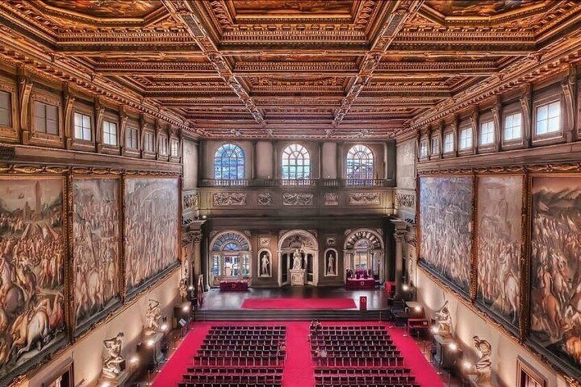 Un salón ornamentado con alfombra roja, techos altos y pinturas clásicas. 1
