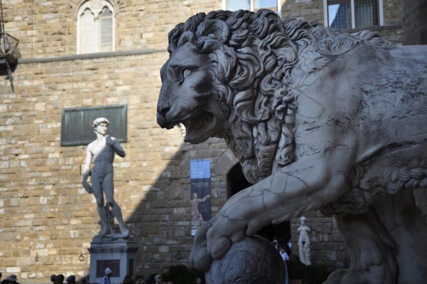 A stone lion statue in front of a building with a brick facade and arched windows. 3