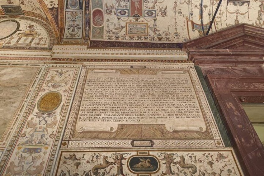 Un fresco detallado con diseños intrincados y un panel central con texto. 4
