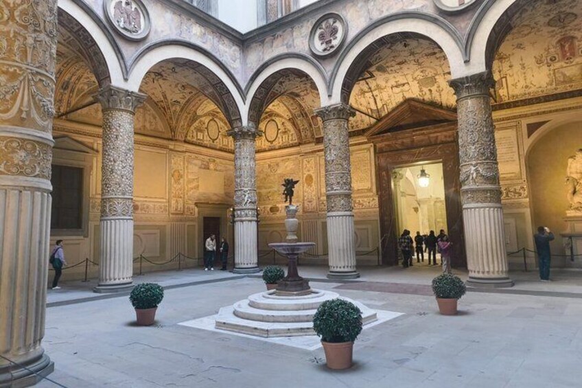 Un patio ornamentado con columnas, una fuente y plantas en macetas. 2