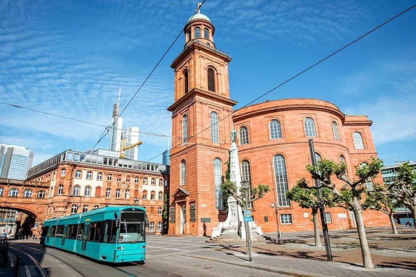 Un bâtiment en briques rouges, doté d’une tour, avec un tramway et une statue au premier plan. 5