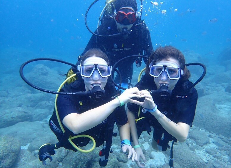 Two scuba divers underwater, one making a heart shape with their hands. 5