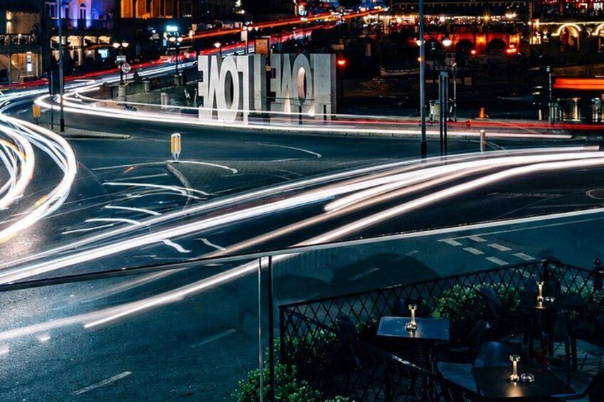 A nighttime city intersection with light trails from moving vehicles. 2