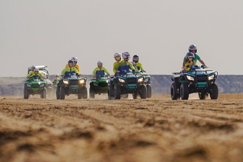Un groupe de personnes conduisant des quads sur un chemin de terre, dans un paysage désertique. 2