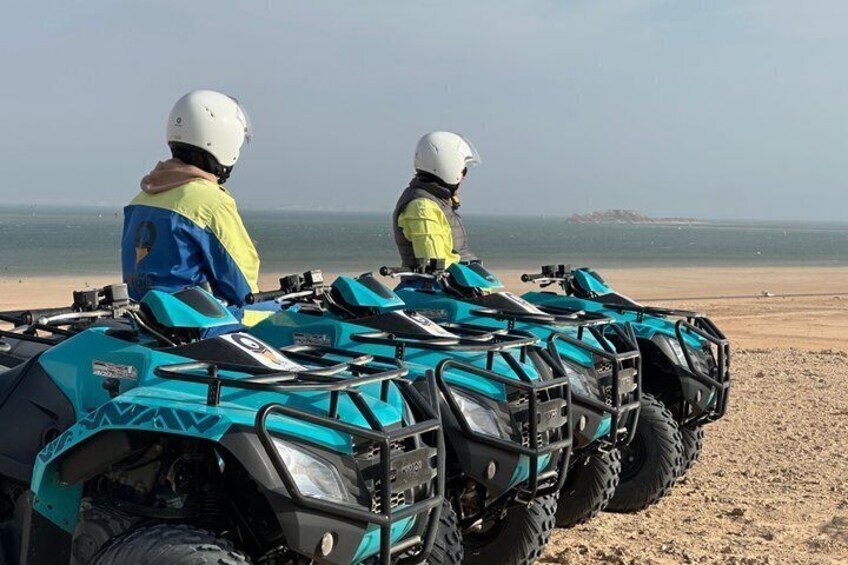 Deux personnes sur des quads, sur une plage de sable, avec l’océan en arrière-plan. 5