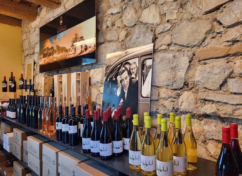 A wine tasting room with a stone wall, a poster of a vineyard, and bottles of wine on display. 5