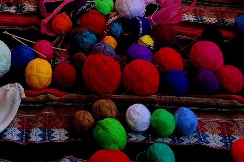 A variety of colorful yarn balls on a patterned fabric. 2