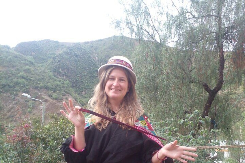 A person with a hat, holding a stick, standing in a natural landscape with hills and trees. 5