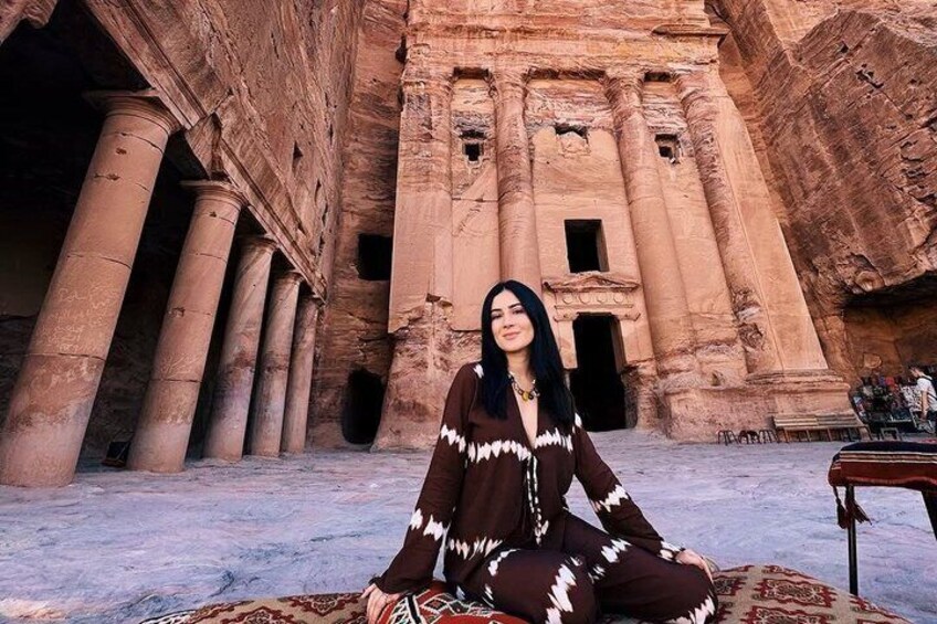 A person sitting in front of a large ancient structure with columns. 1