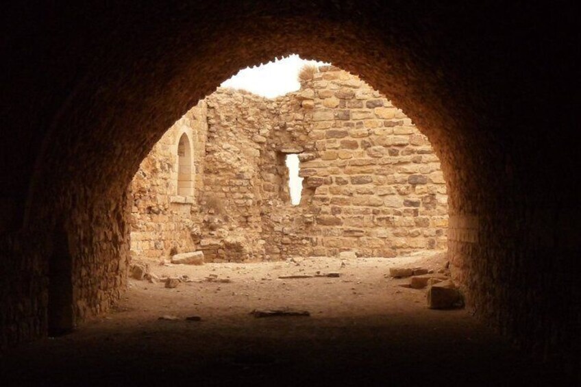 An ancient stone structure with an arched doorway leading to a courtyard. 4