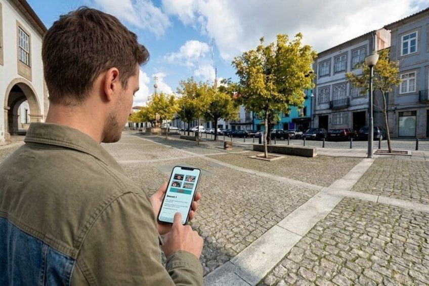 Une personne utilise un téléphone intelligent sur une place pavée, avec des bâtiments et des arbres en arrière-plan. 4