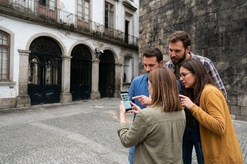 Un groupe de personnes se tient dans une rue pavée, avec des bâtiments historiques en arrière-plan. 1
