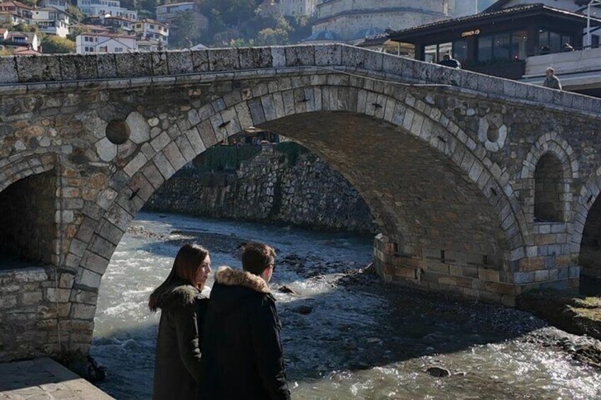A stone bridge over a river with people standing underneath. 1