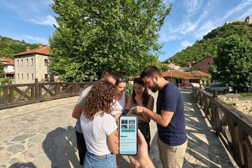 A group of people on a stone bridge with a smartphone displaying a map. 3