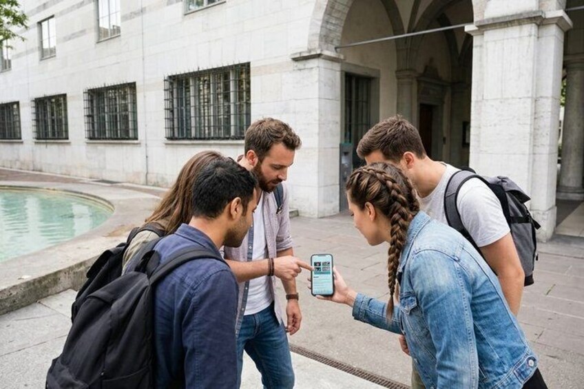 A group of people standing on a sidewalk, looking at a smartphone. 5