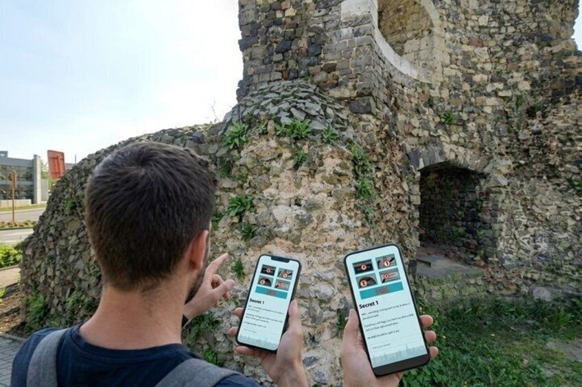 A person using two smartphones with historical information about a stone structure. 3