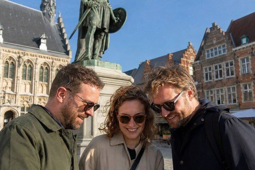 Three people standing in front of a historic building with a statue. 1