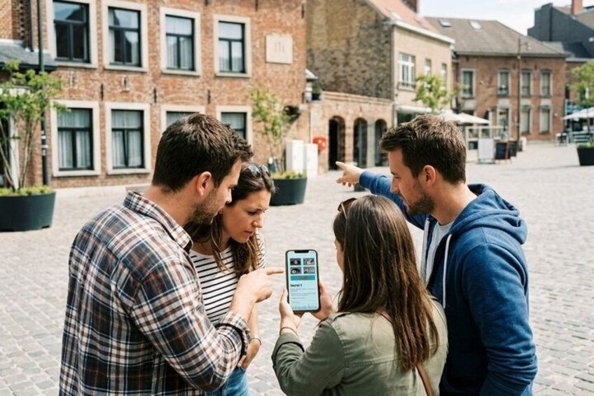 A group of people standing on a cobblestone street, looking at a smartphone. 1