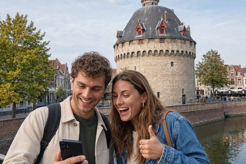 A couple standing by a canal with a historic tower in the background. 4