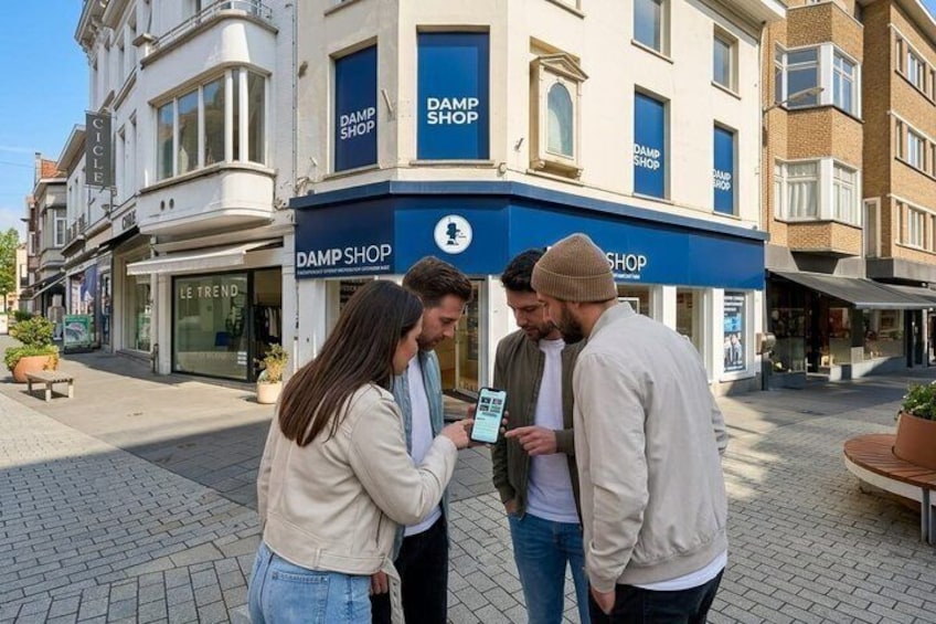 Trois personnes se tiennent sur un trottoir, devant un bâtiment sur lequel on peut lire l'inscription « DAMP SHOP ». 4