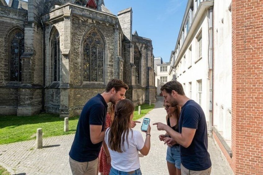 Un groupe de personnes se tient dans une cour, avec un bâtiment historique en arrière-plan. 3