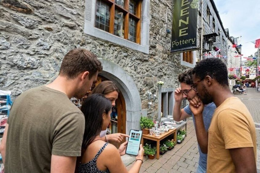 A group of people standing outside a building with a sign that reads 'GREEN Pottery.' 1