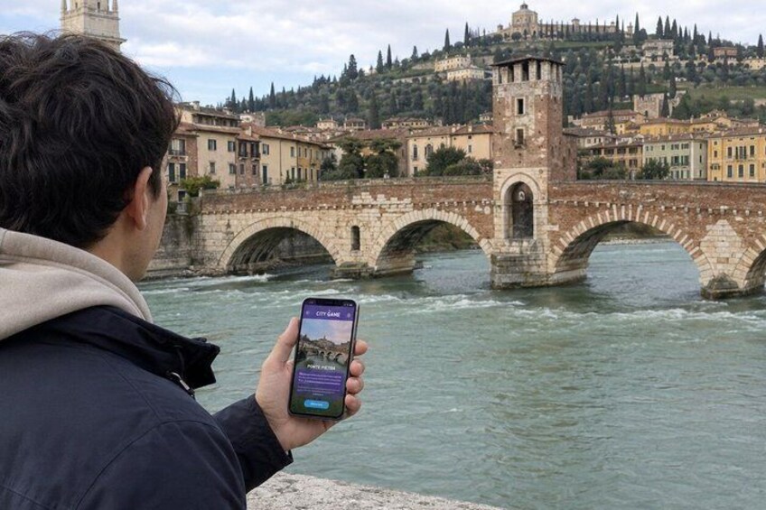 Eine Person fotografiert eine Stebrücke über dem Wasser, im Hintergrund sind Gebäude zu sehen. 2