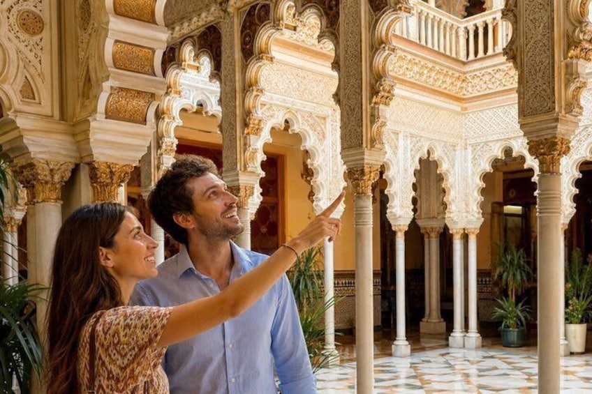Un hombre y una mujer en un patio ricamente decorado con arcos y columnas intrincados. 2