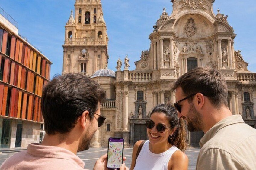 Un edificio histórico con arquitectura elaborada, una persona tomando una foto y otra mirando el teléfono. 4