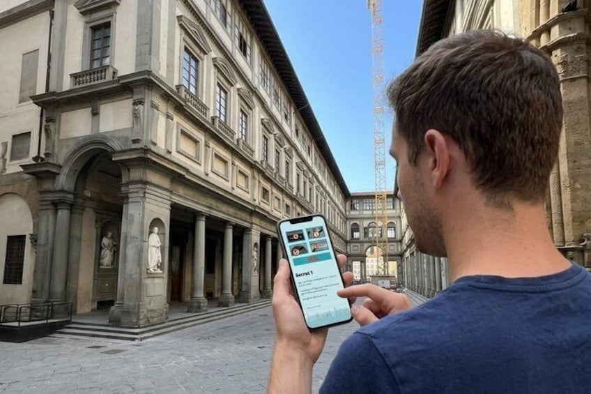 En person bruger en smartphone foran en historisk bygning med søjler og statuer. 5