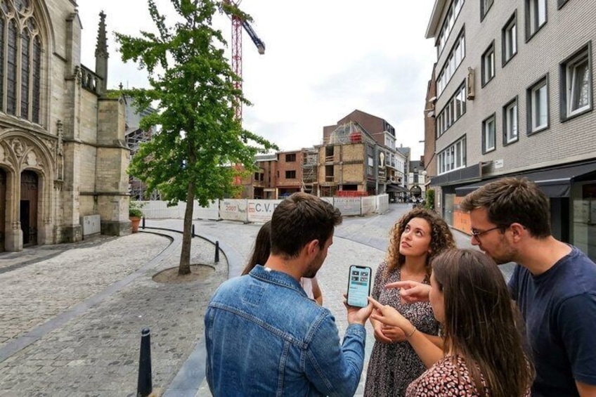 A group of people gathered around a smartphone, possibly using a map or guide app. 1