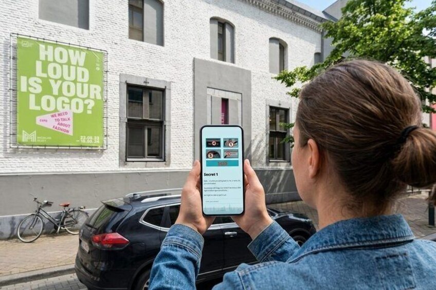 A person using a smartphone, a building with a green sign, and a bicycle parked on the sidewalk. 5