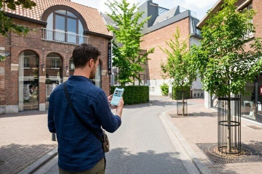 A man walking on a street with a smartphone, buildings with brick facades, and trees. 4